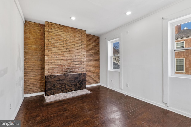 unfurnished living room with brick wall and dark wood-type flooring