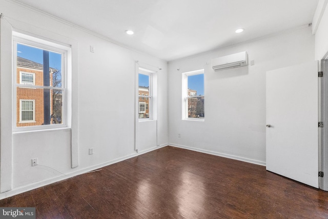 spare room featuring ornamental molding, an AC wall unit, and dark hardwood / wood-style floors