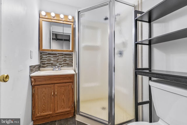 bathroom with a shower with door, vanity, toilet, and decorative backsplash