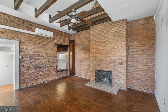 unfurnished living room featuring a wall mounted AC, a fireplace, beamed ceiling, dark hardwood / wood-style floors, and brick wall