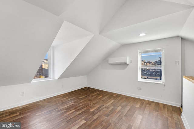 additional living space featuring dark wood-type flooring, lofted ceiling, and a wall mounted air conditioner