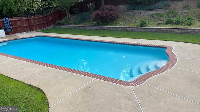 view of swimming pool with a patio area, a fenced backyard, and a lawn