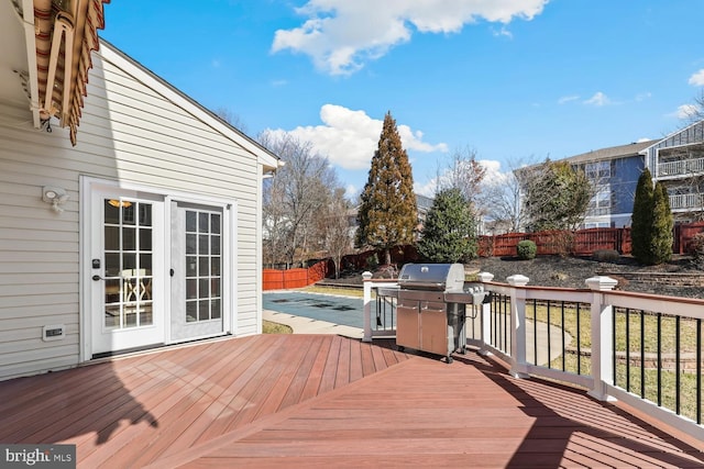 wooden terrace with a grill, a fenced in pool, a fenced backyard, and french doors