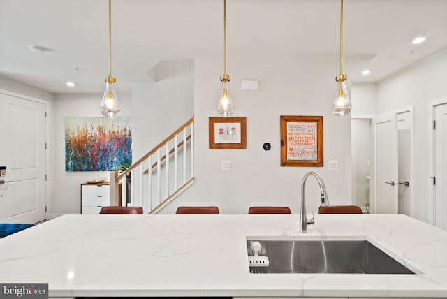 kitchen with decorative light fixtures, sink, and a breakfast bar area