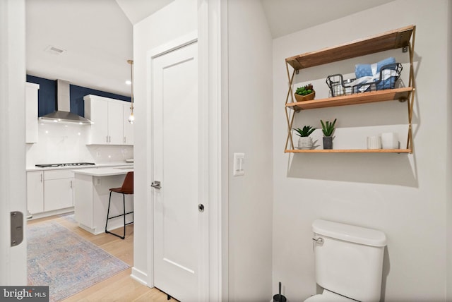 bathroom with hardwood / wood-style flooring, toilet, and tasteful backsplash