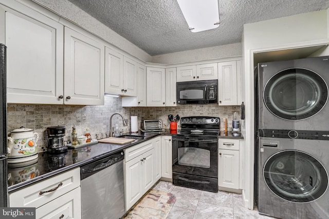 kitchen featuring black appliances, white cabinetry, decorative backsplash, sink, and stacked washing maching and dryer