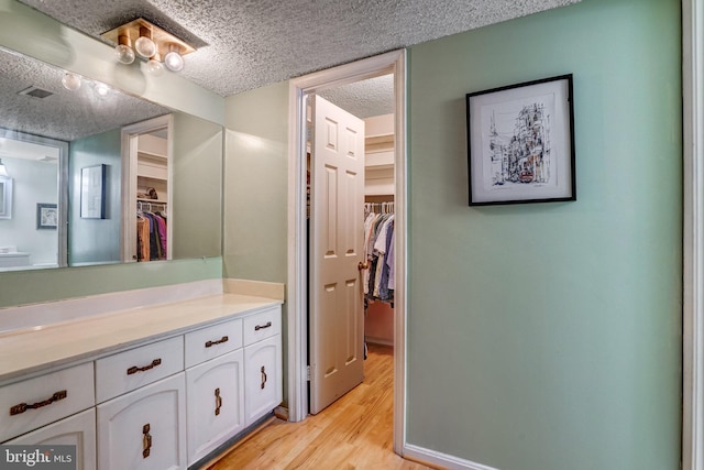 bathroom featuring vanity, wood-type flooring, and a textured ceiling