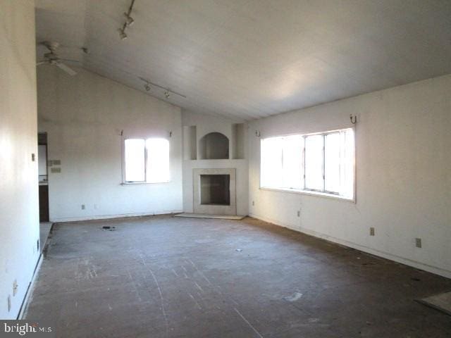 unfurnished living room featuring ceiling fan, track lighting, and lofted ceiling