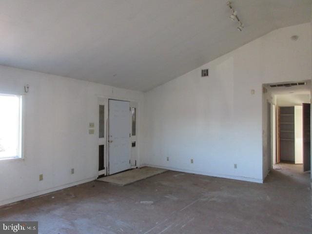 spare room with track lighting and vaulted ceiling