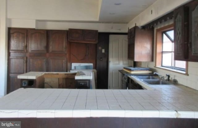 kitchen with sink, tile counters, and kitchen peninsula