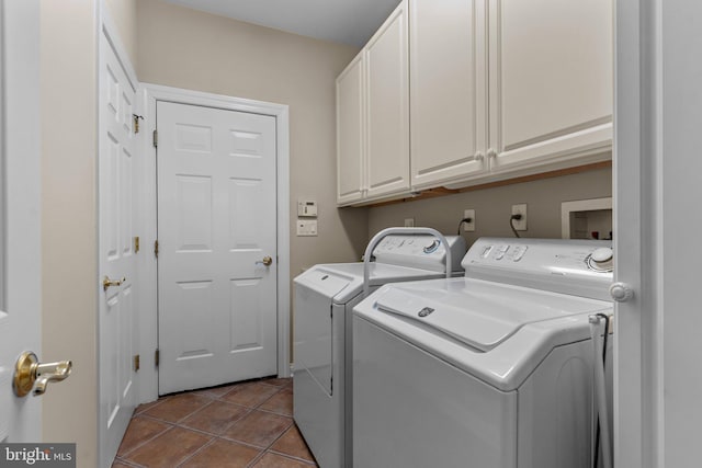 clothes washing area featuring light tile patterned floors, washing machine and dryer, and cabinets