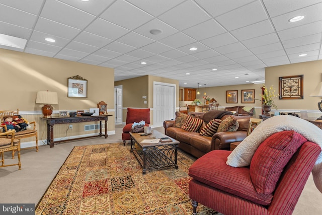 living room featuring light carpet and a paneled ceiling