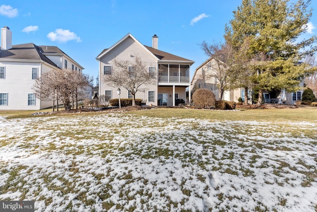 snow covered property featuring a sunroom and a lawn