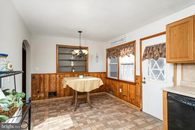 dining space featuring an inviting chandelier and wood walls