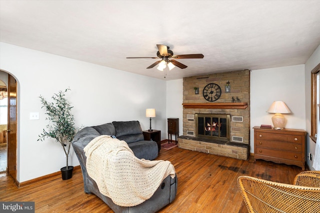 living room with ceiling fan, wood-type flooring, and a fireplace