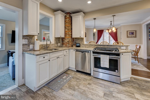 kitchen with stainless steel appliances, light stone countertops, kitchen peninsula, sink, and white cabinetry