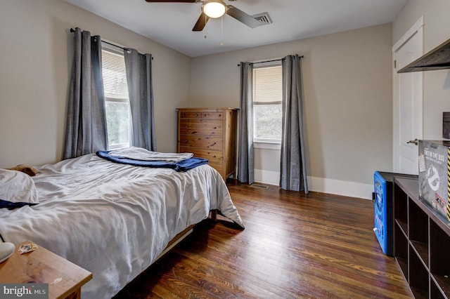 bedroom with ceiling fan, dark wood-type flooring, and multiple windows