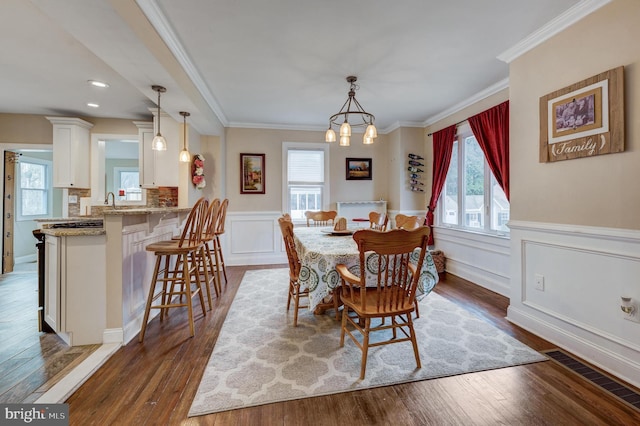 dining area featuring a healthy amount of sunlight, dark wood-type flooring, an inviting chandelier, and crown molding