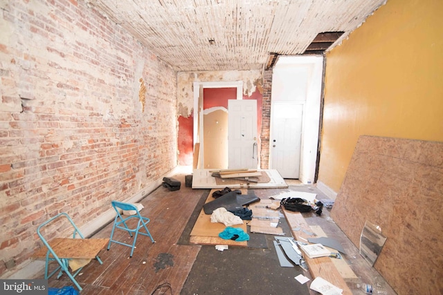 miscellaneous room with brick wall and wood-type flooring