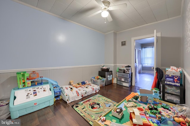 rec room with crown molding, ceiling fan, and dark hardwood / wood-style flooring