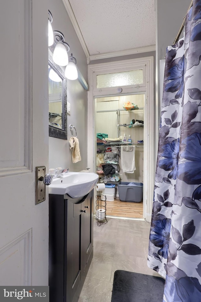 bathroom with crown molding, vanity, and a textured ceiling