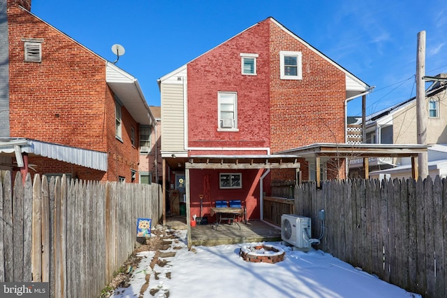 snow covered rear of property with ac unit