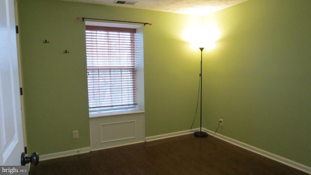 spare room with a textured ceiling and dark hardwood / wood-style floors