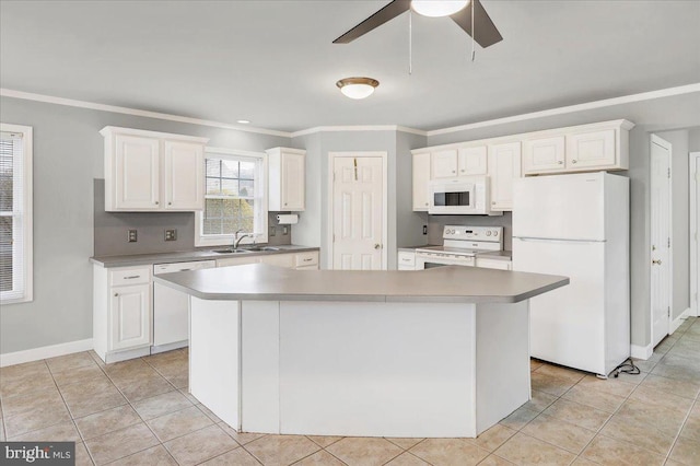 kitchen with white appliances, a center island, ornamental molding, sink, and white cabinetry