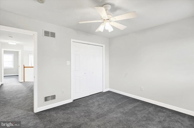 unfurnished bedroom with dark colored carpet, ceiling fan, and a closet