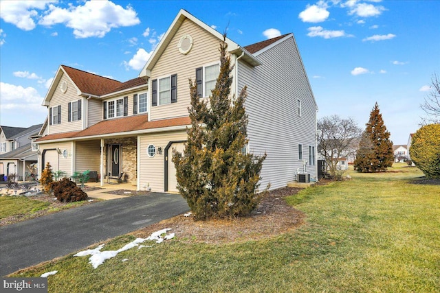 view of front of home with a front yard, a garage, and central air condition unit