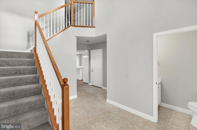 stairway featuring a high ceiling and tile patterned floors