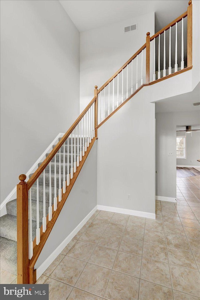 stairway with a high ceiling and tile patterned flooring