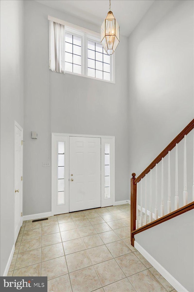 foyer featuring a high ceiling, a notable chandelier, and light tile patterned floors