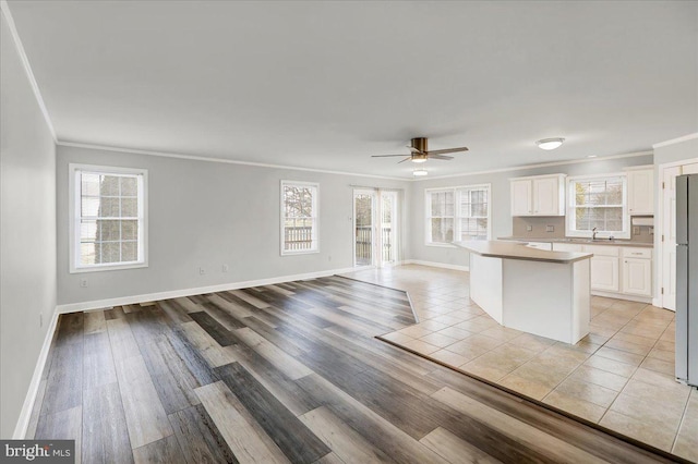 kitchen with white cabinets, ceiling fan, crown molding, and a kitchen island