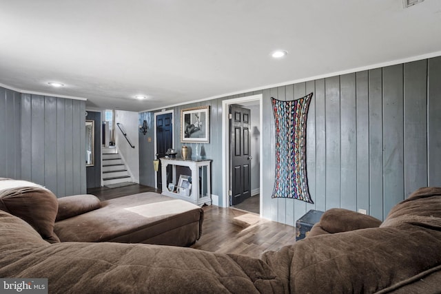 living room featuring wood-type flooring, ornamental molding, and wooden walls