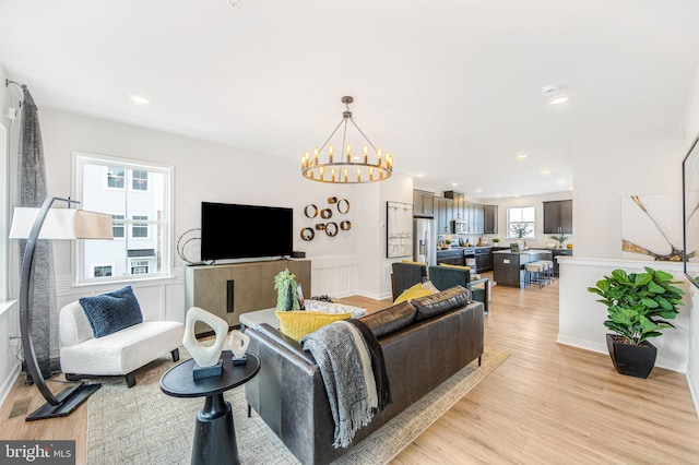 living room featuring light wood-type flooring and a notable chandelier