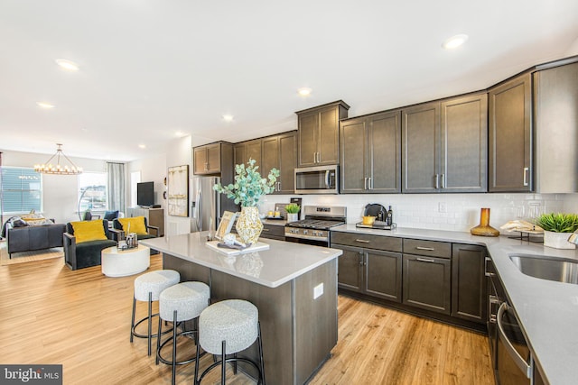 kitchen with light hardwood / wood-style floors, decorative backsplash, a kitchen island, a breakfast bar area, and appliances with stainless steel finishes