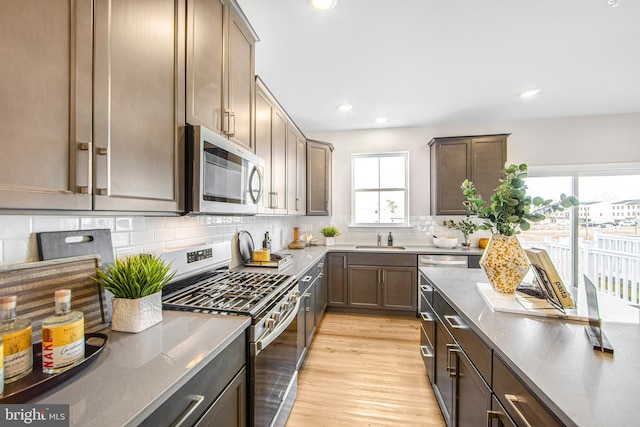 kitchen with appliances with stainless steel finishes, tasteful backsplash, light hardwood / wood-style flooring, and sink