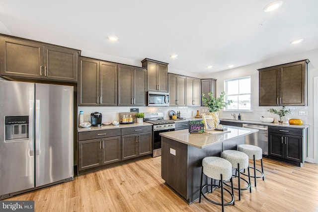 kitchen featuring stainless steel appliances, a center island, backsplash, and a breakfast bar area