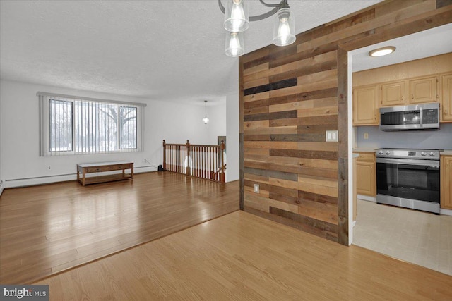 kitchen featuring pendant lighting, light brown cabinets, stainless steel appliances, wooden walls, and light hardwood / wood-style flooring