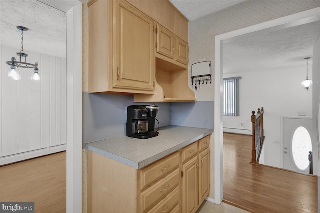 kitchen with a textured ceiling, light brown cabinetry, hanging light fixtures, and a baseboard radiator