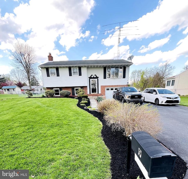 split foyer home featuring a garage and a front yard