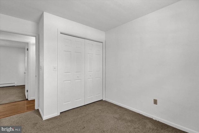 unfurnished bedroom featuring a closet, a baseboard heating unit, and carpet flooring