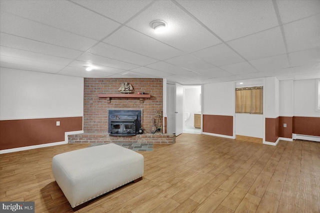 living room with a paneled ceiling, a wood stove, and hardwood / wood-style flooring