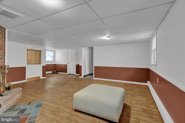 living area featuring baseboard heating, wood-type flooring, and a drop ceiling