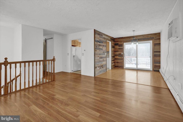 empty room featuring wooden walls, a textured ceiling, and hardwood / wood-style flooring