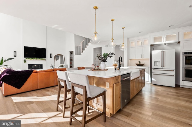 kitchen with pendant lighting, white cabinetry, a kitchen island with sink, appliances with stainless steel finishes, and a breakfast bar area