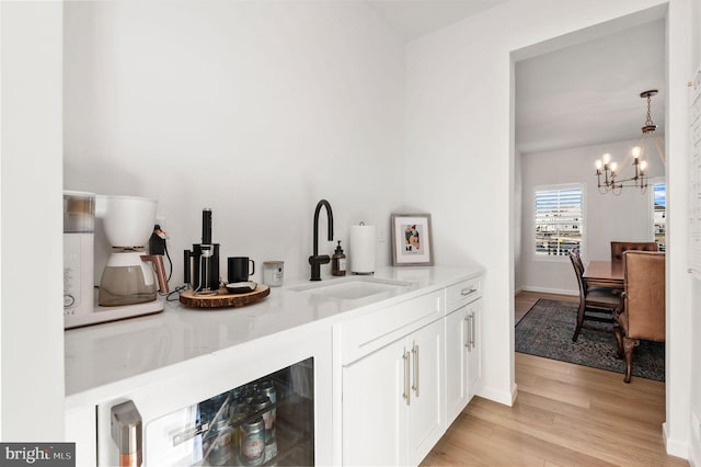 bar featuring white cabinetry, a notable chandelier, pendant lighting, light stone counters, and sink