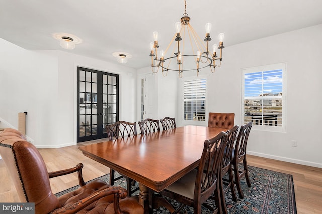 dining room featuring french doors, an inviting chandelier, and light hardwood / wood-style flooring