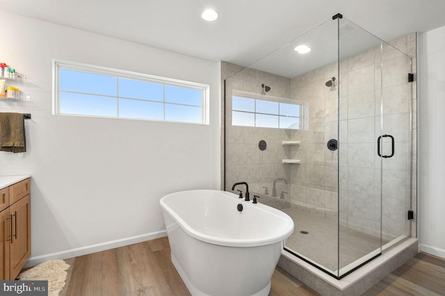 bathroom with hardwood / wood-style flooring, plenty of natural light, vanity, and plus walk in shower